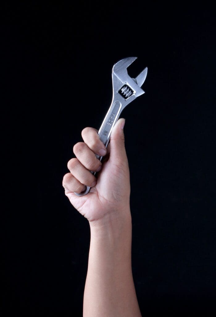 Las Vegas plumbing worker holding a wrench while servicing plumbing equipment during a water heater maintenance job.